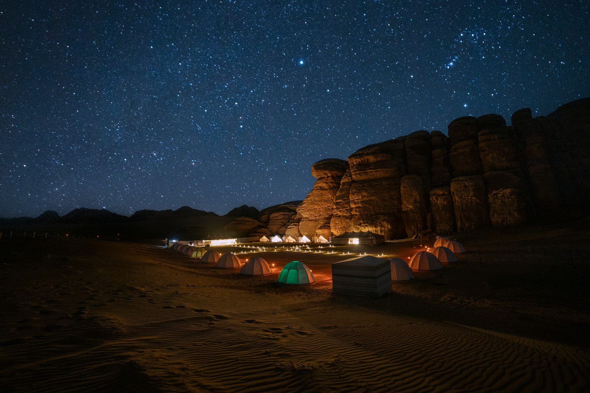 A tent set up in the middle of a desert at night