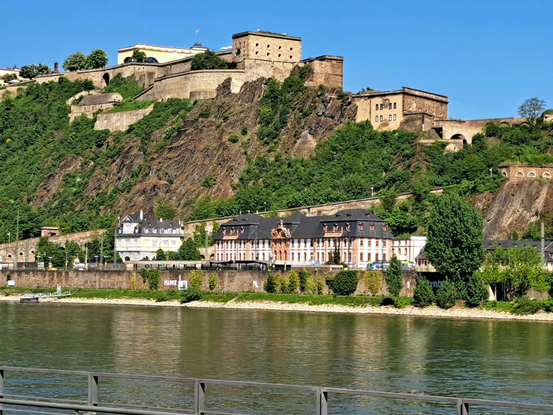 A fortress sits atop a hill by a river.