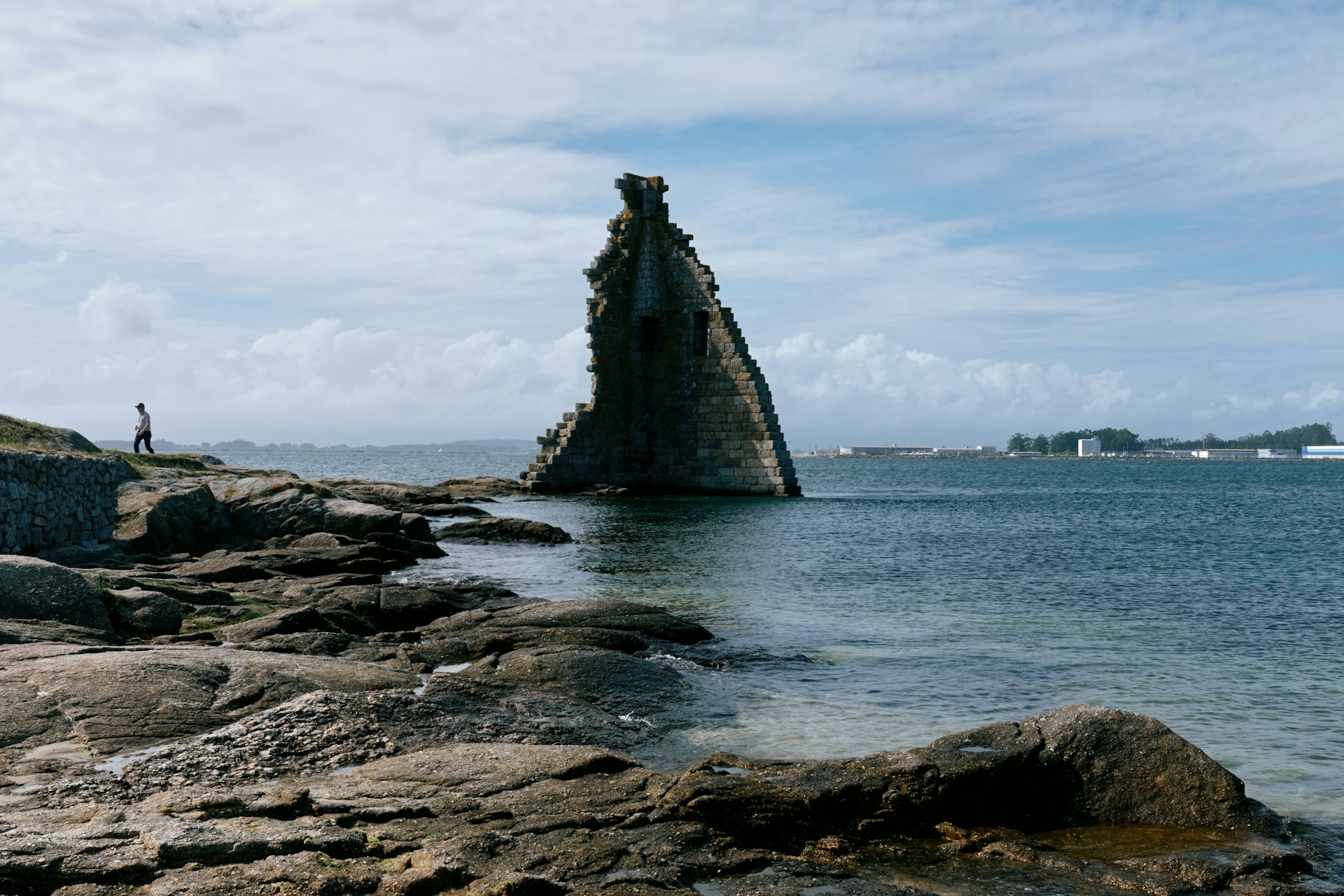 a person standing on a rocky shore next to a body of water