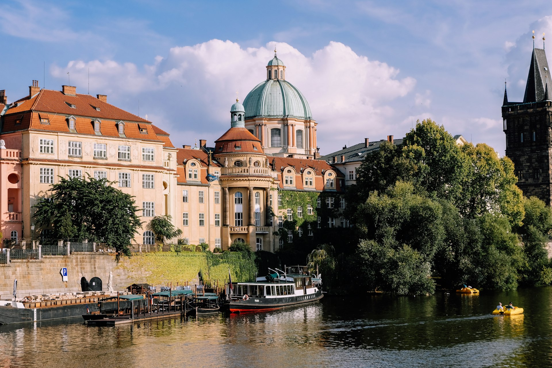 red and white boat on river near green trees and brown concrete building during daytime