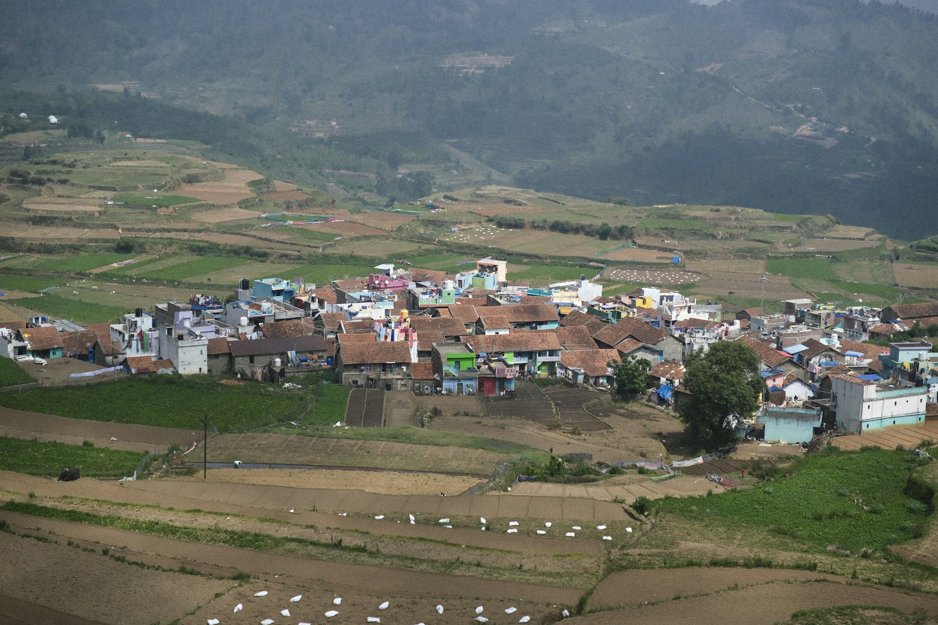 Village nestled in the mountains with surrounding fields.