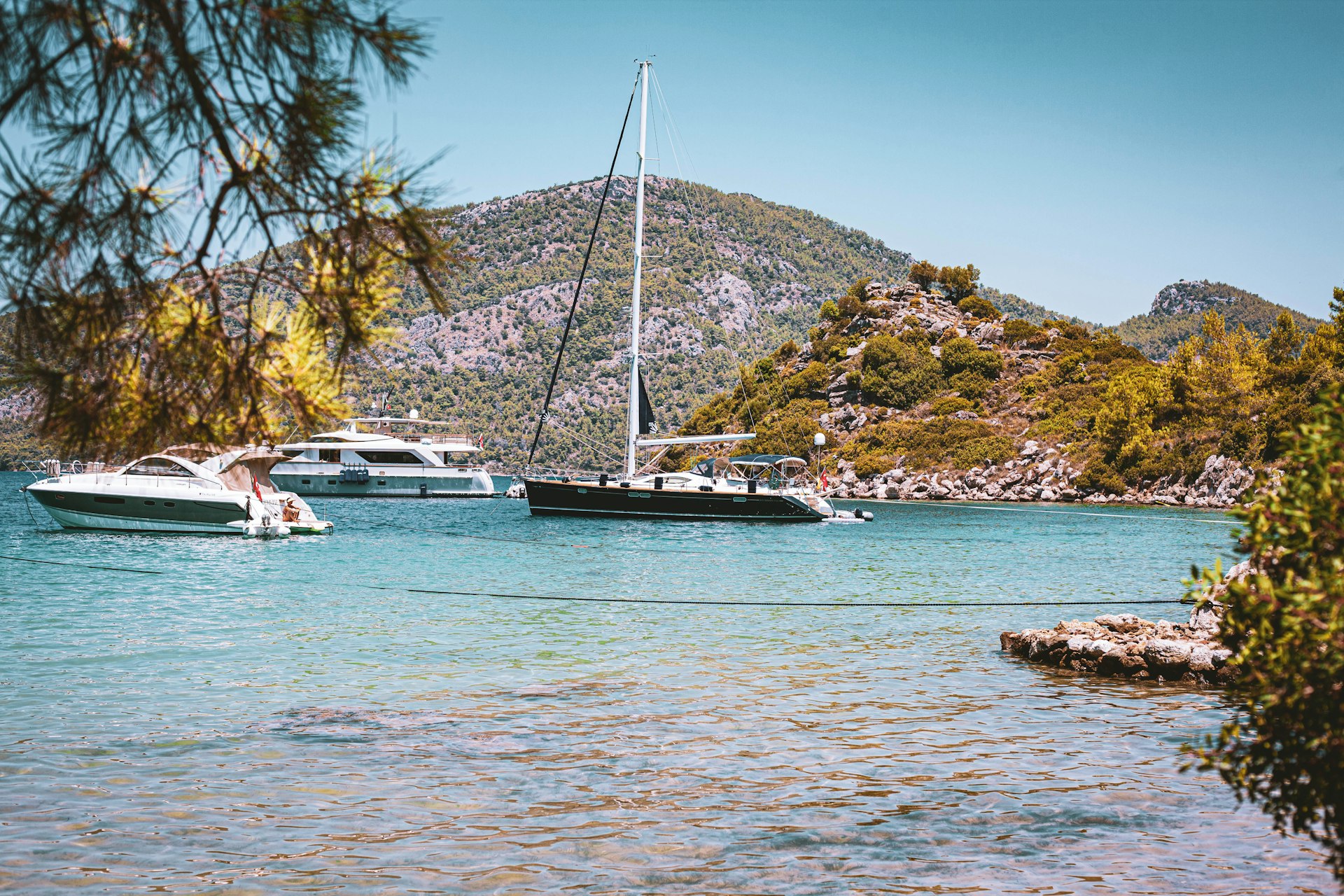 white and blue boat on sea near green and brown mountain under blue sky during daytime