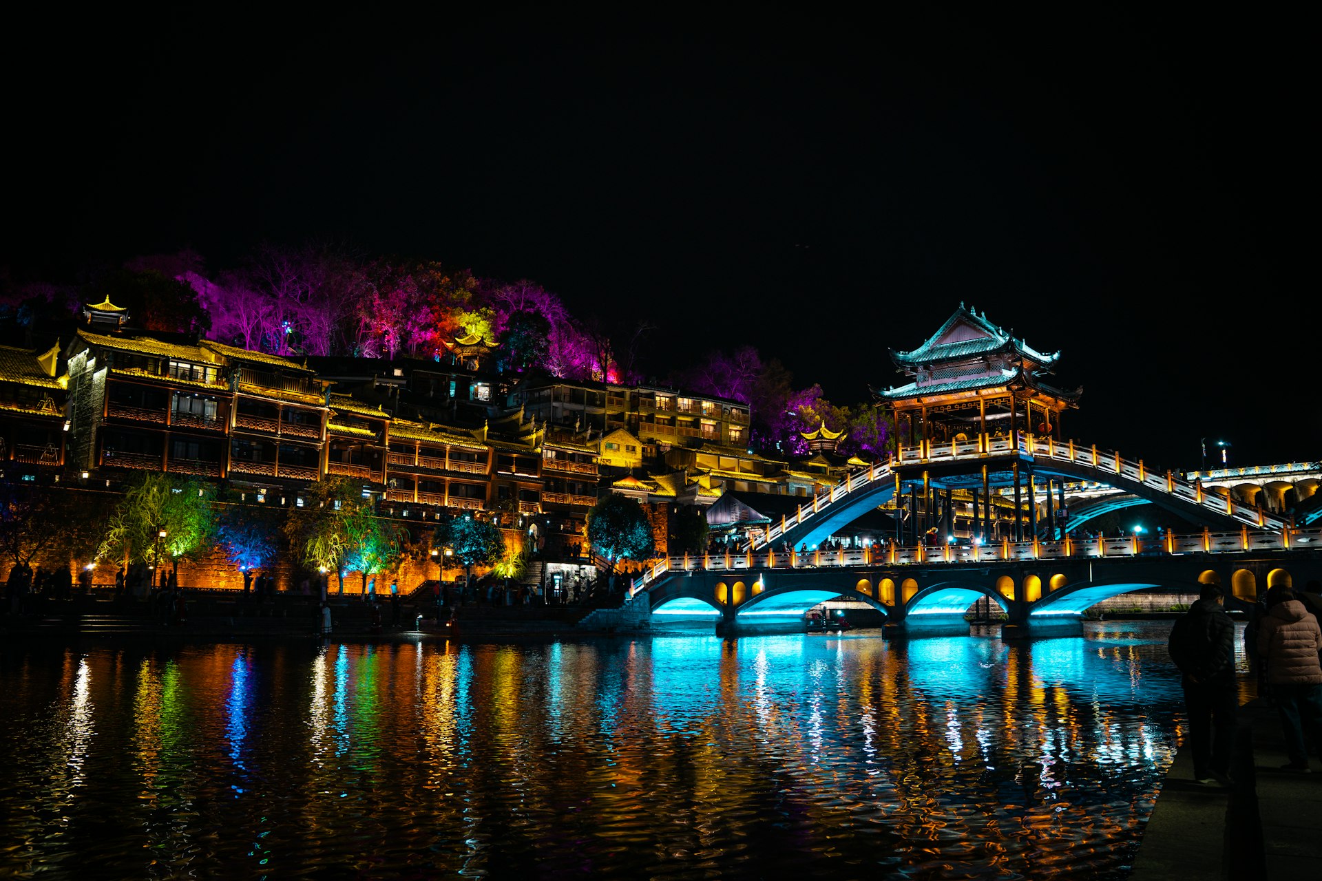 Beautifully lit buildings and bridge at night.