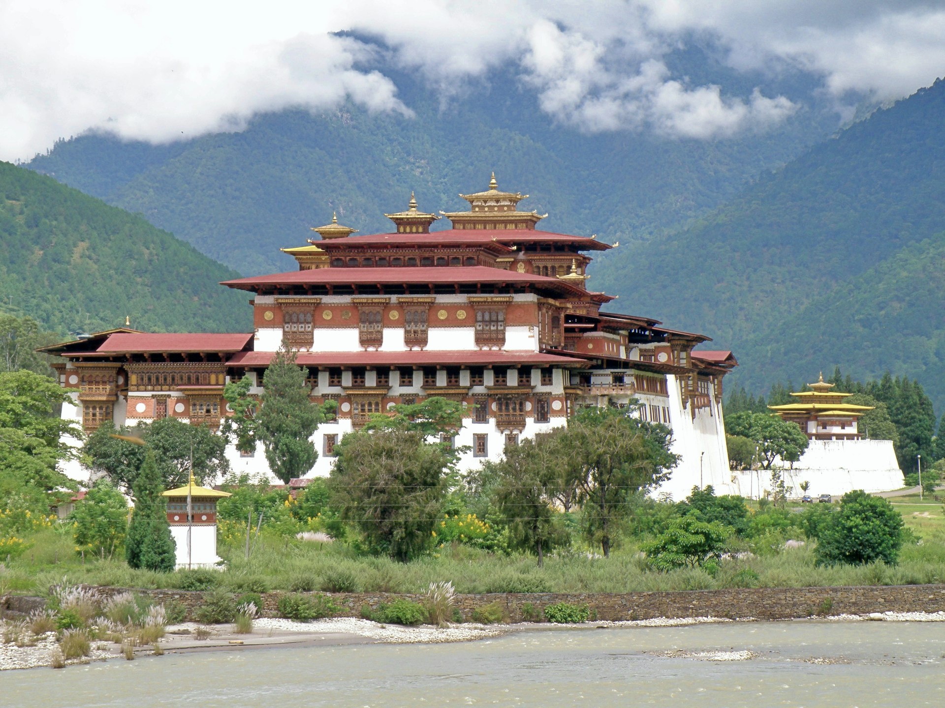 A large white and brown building sitting on top of a lush green hillside