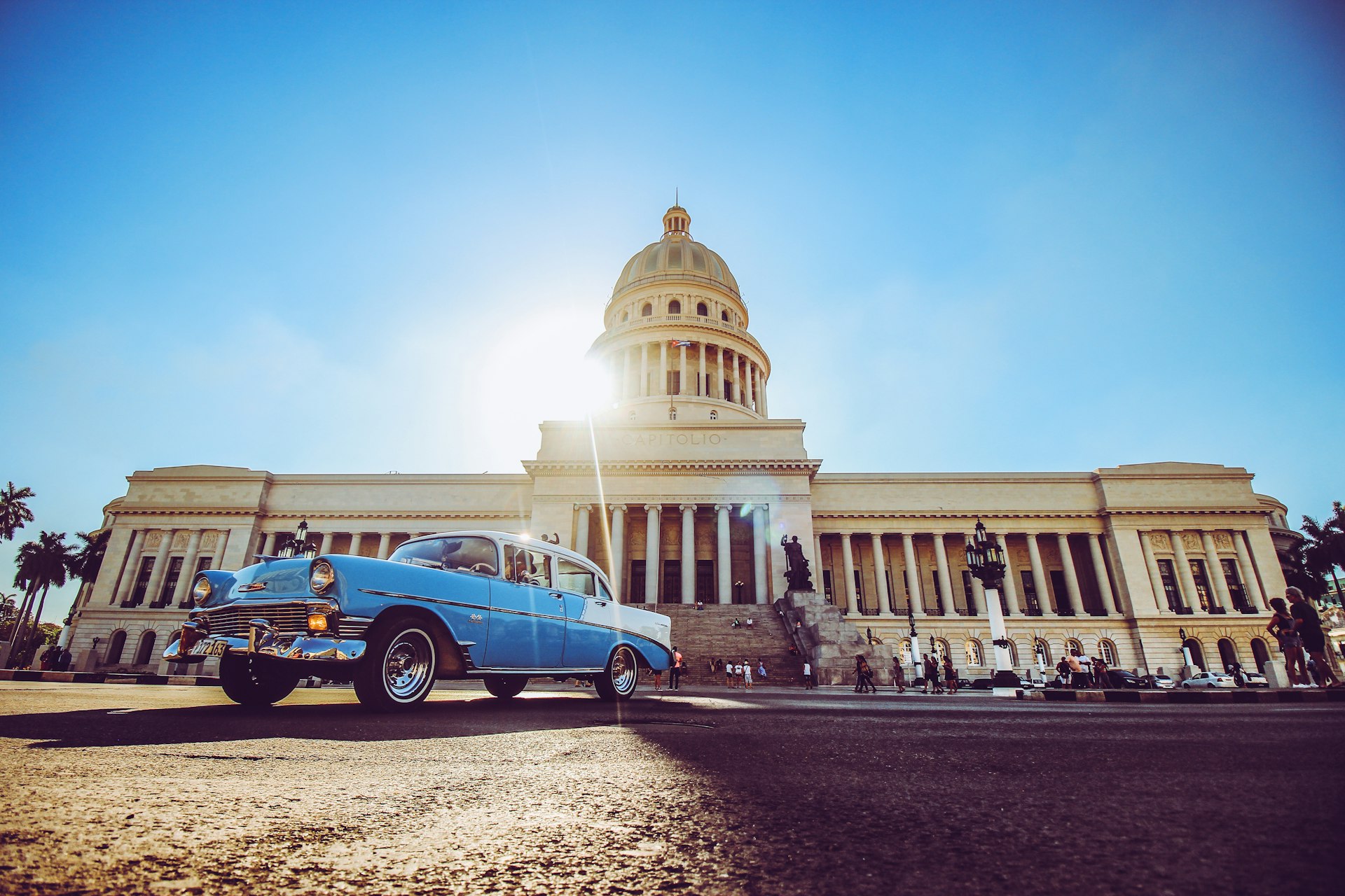blue and white volkswagen beetle parked near white concrete building during daytime
