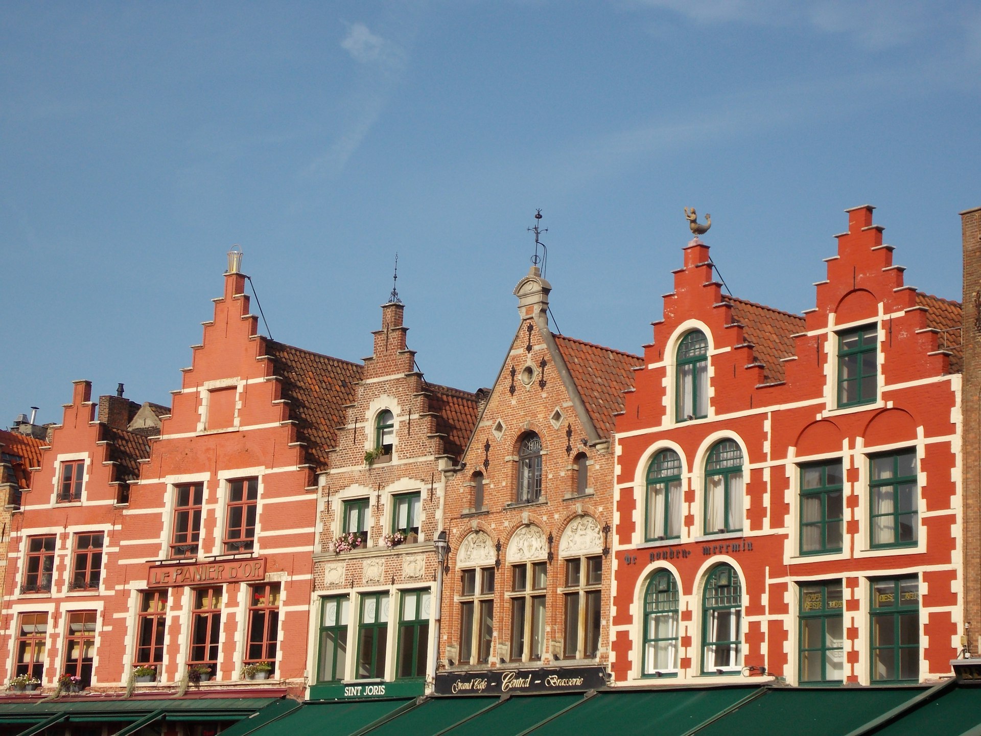 a row of red brick buildings with green awnings