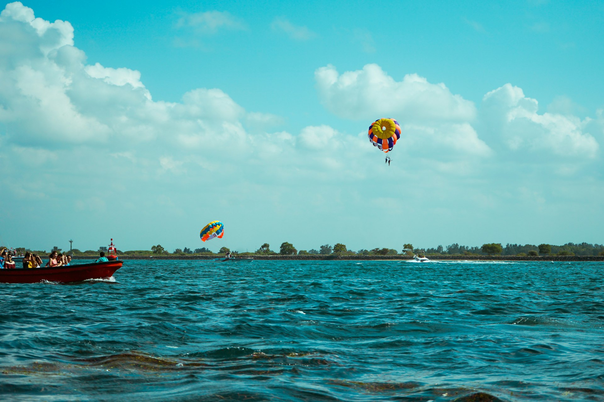 people riding red and yellow parachute over blue sea under blue sky during daytime