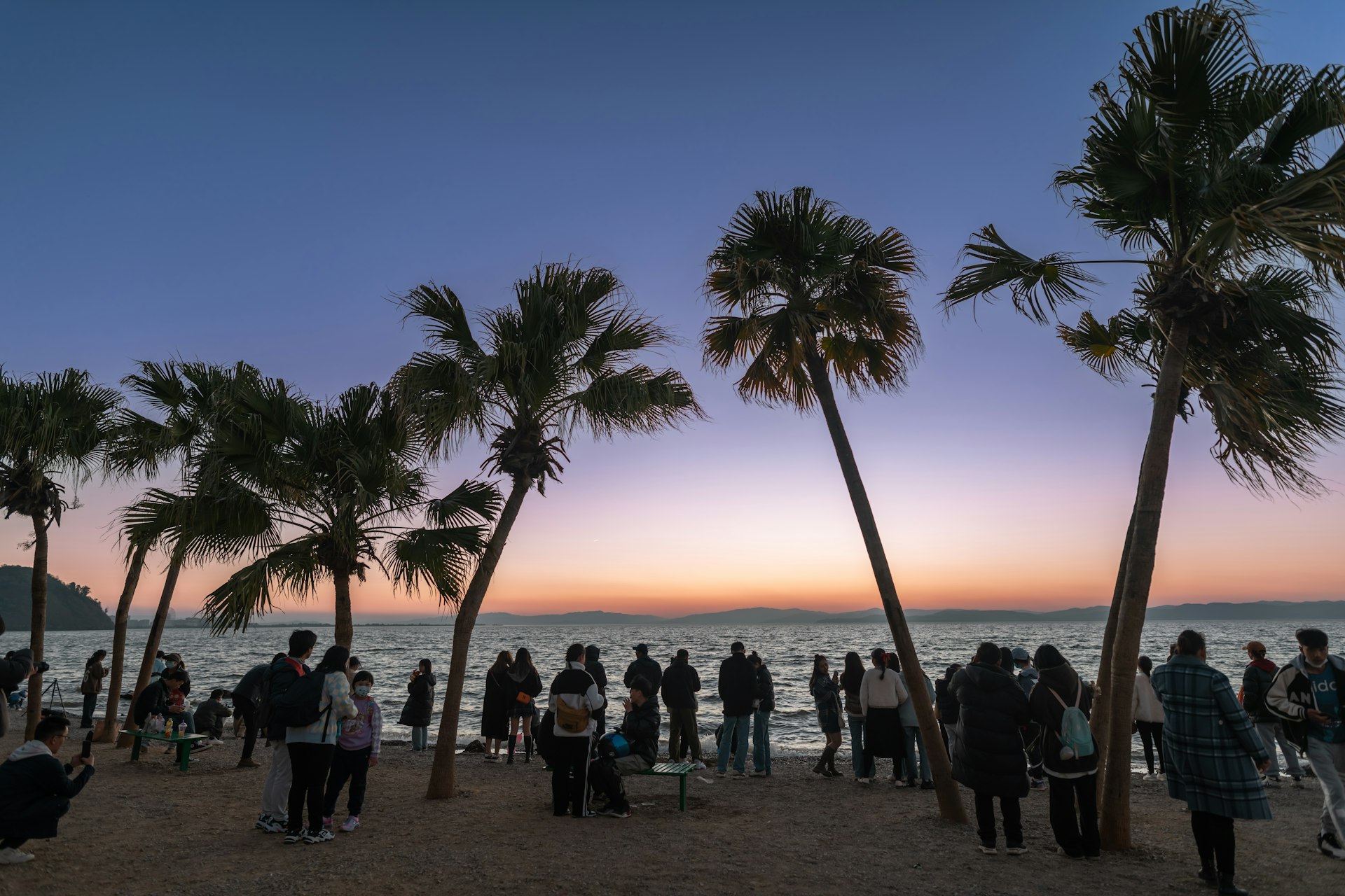 a group of people standing on top of a sandy beach