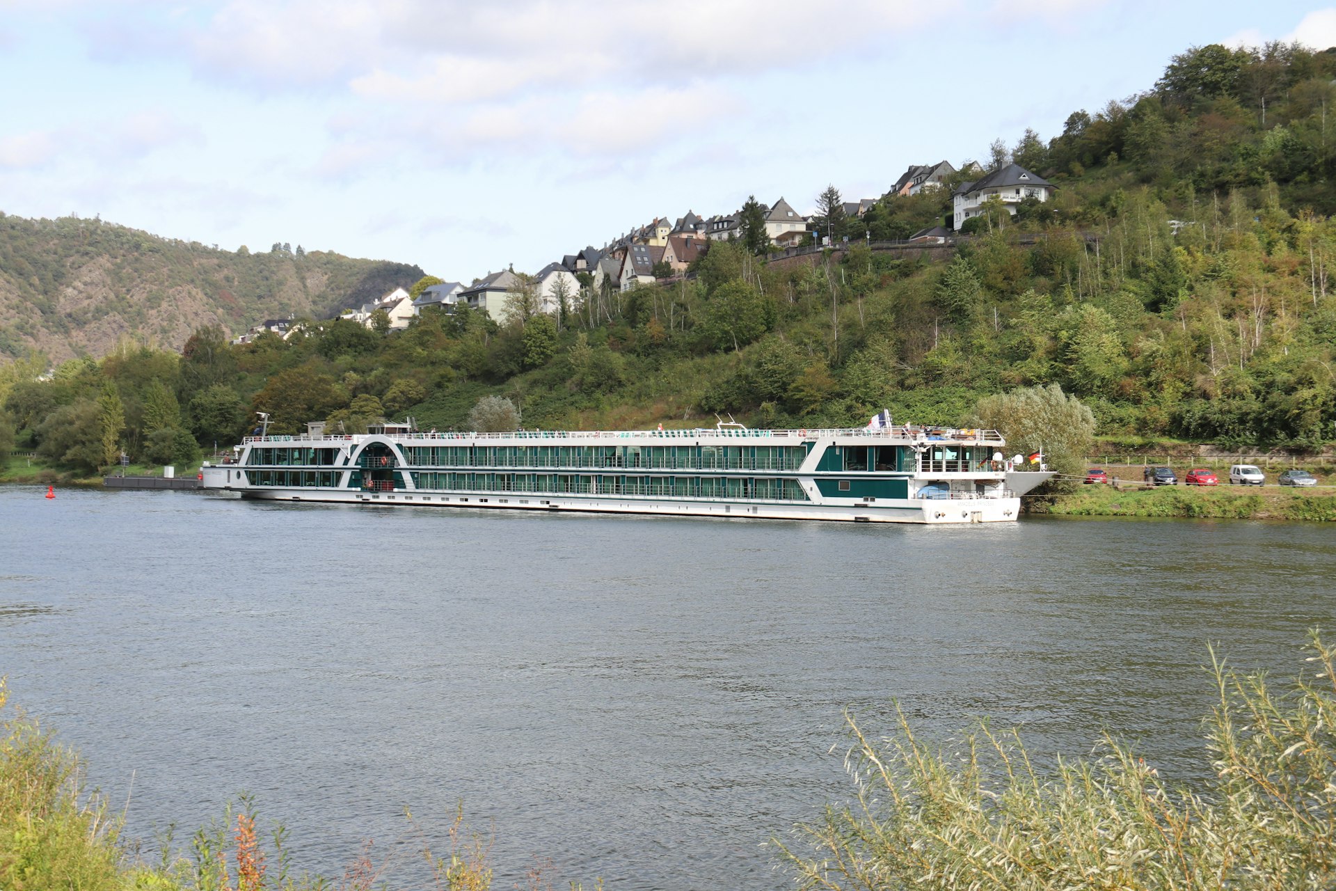 a large boat on a river near a forest