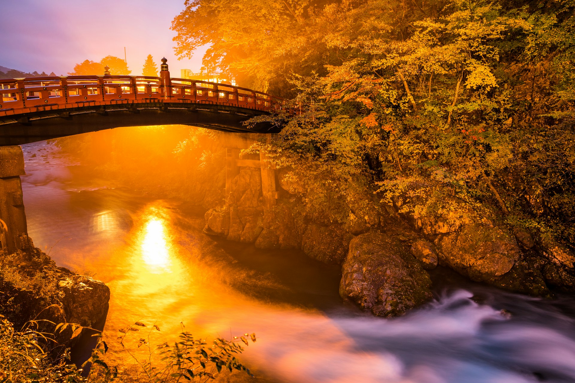 brown and black bridge surrounded by body of water and trees at golden hour