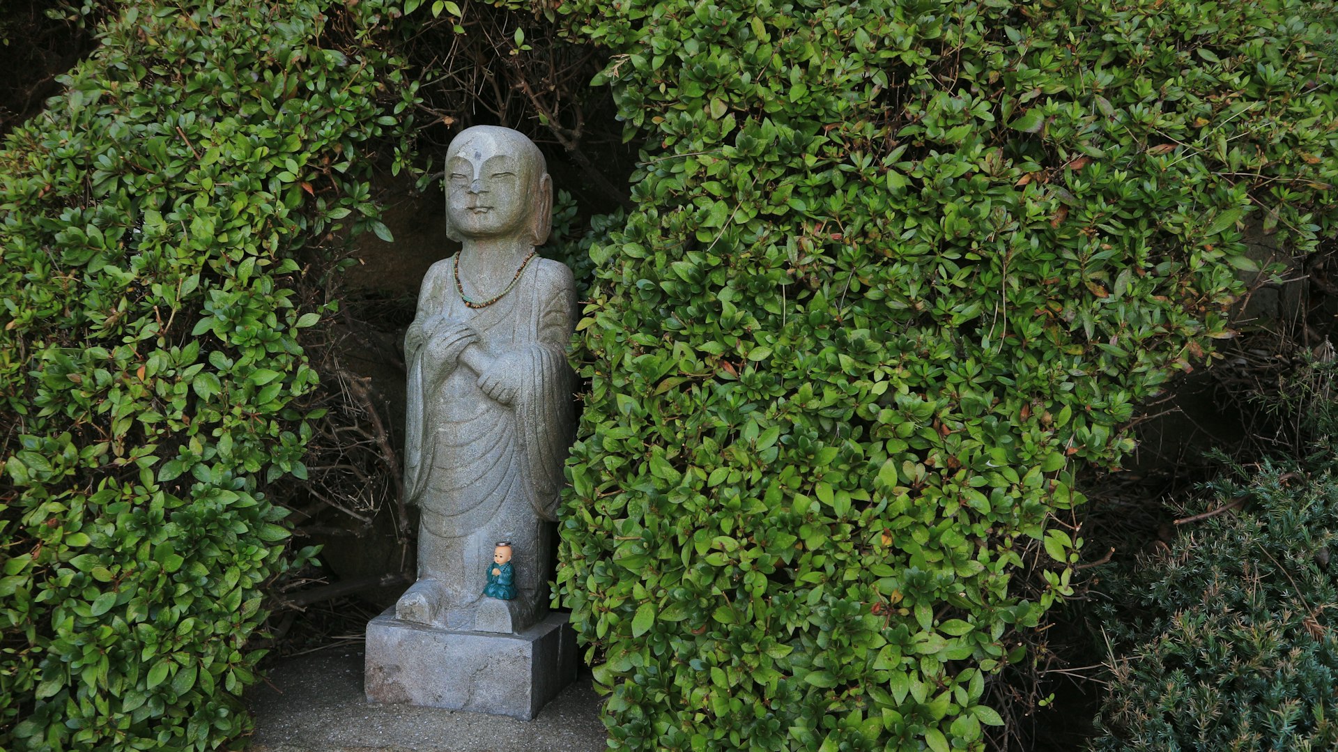 woman statue in the middle of green plants