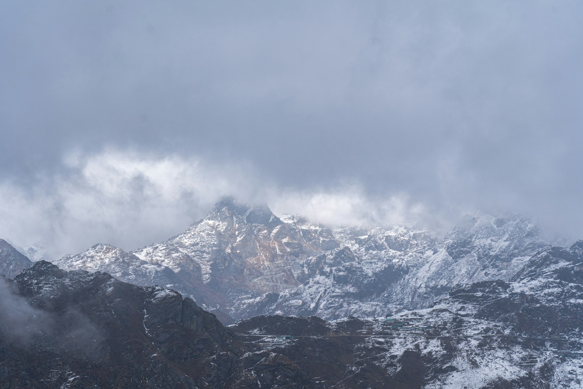a snow covered mountain range under a cloudy sky