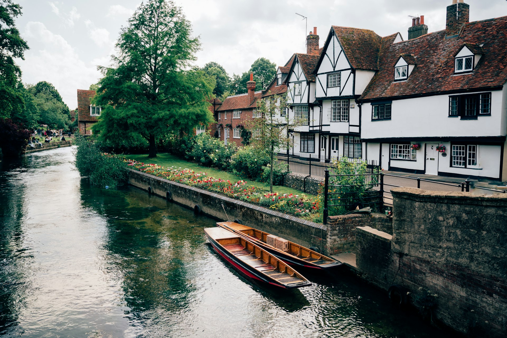 A boat floating down a river next to a row of houses
