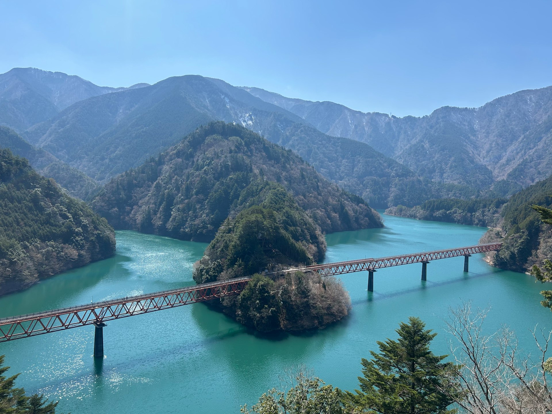 A bridge spans across turquoise waters and mountains.