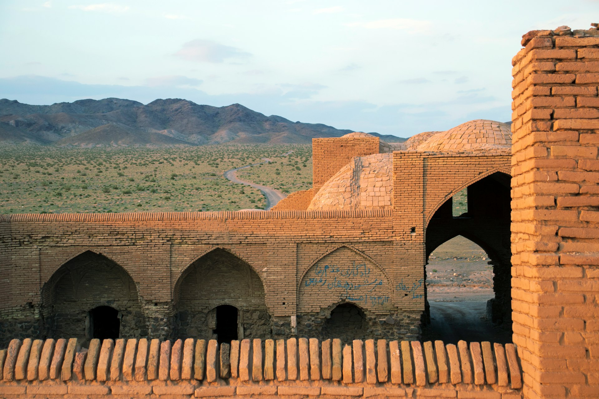 a brick building with arches and arches in front of a mountain range