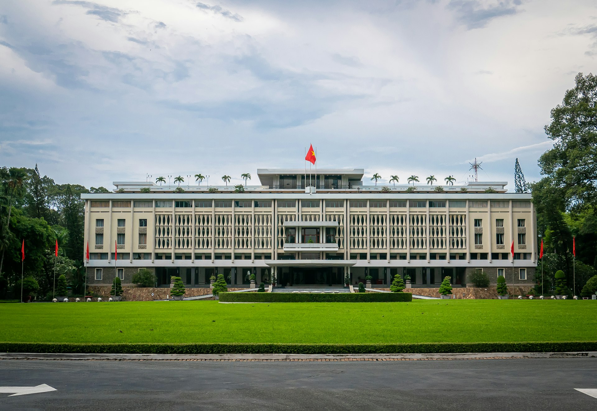 white concrete building with flag on top under white clouds during daytime