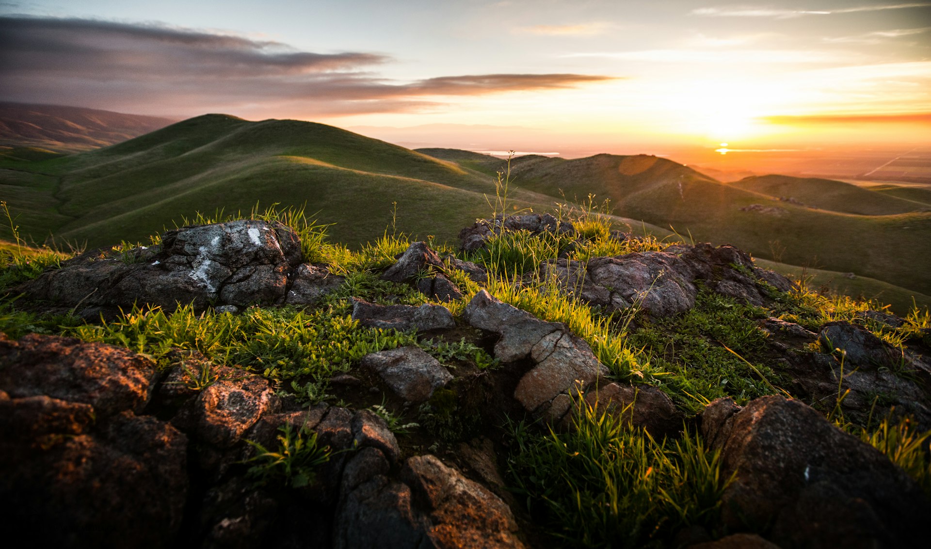 the sun is setting over the mountains and rocks