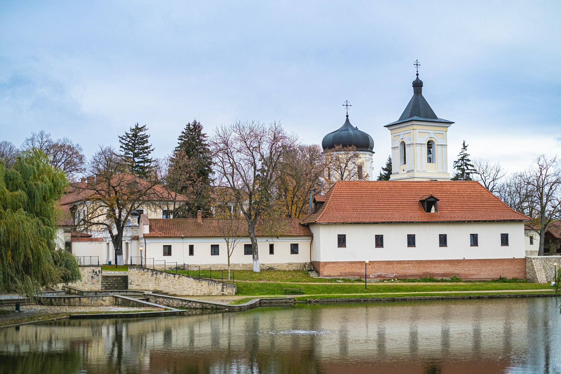 A large white building with a red roof next to a body of water