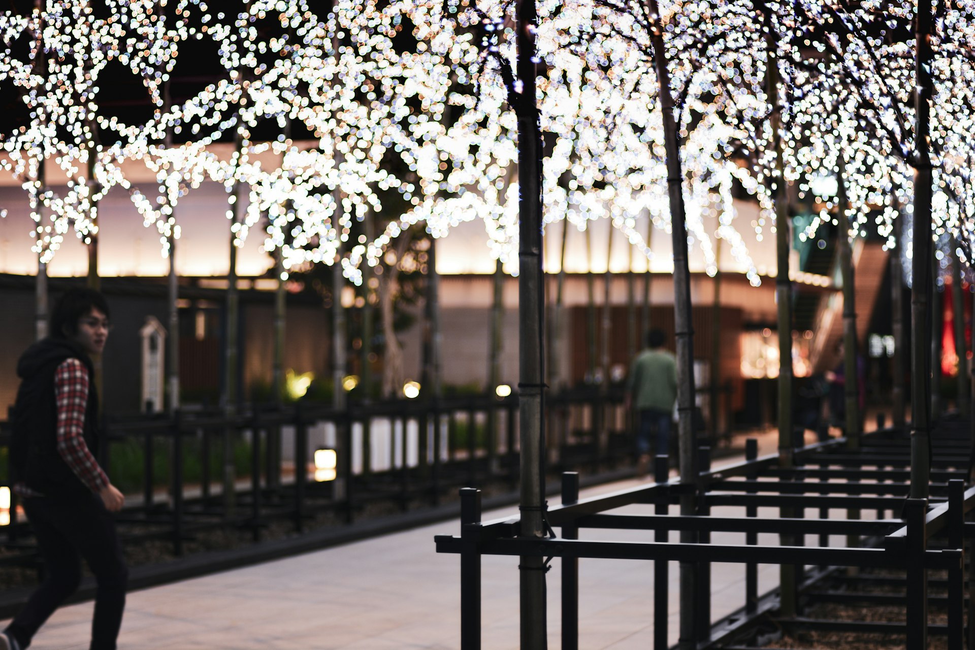 person in green jacket standing near black metal fence during daytime