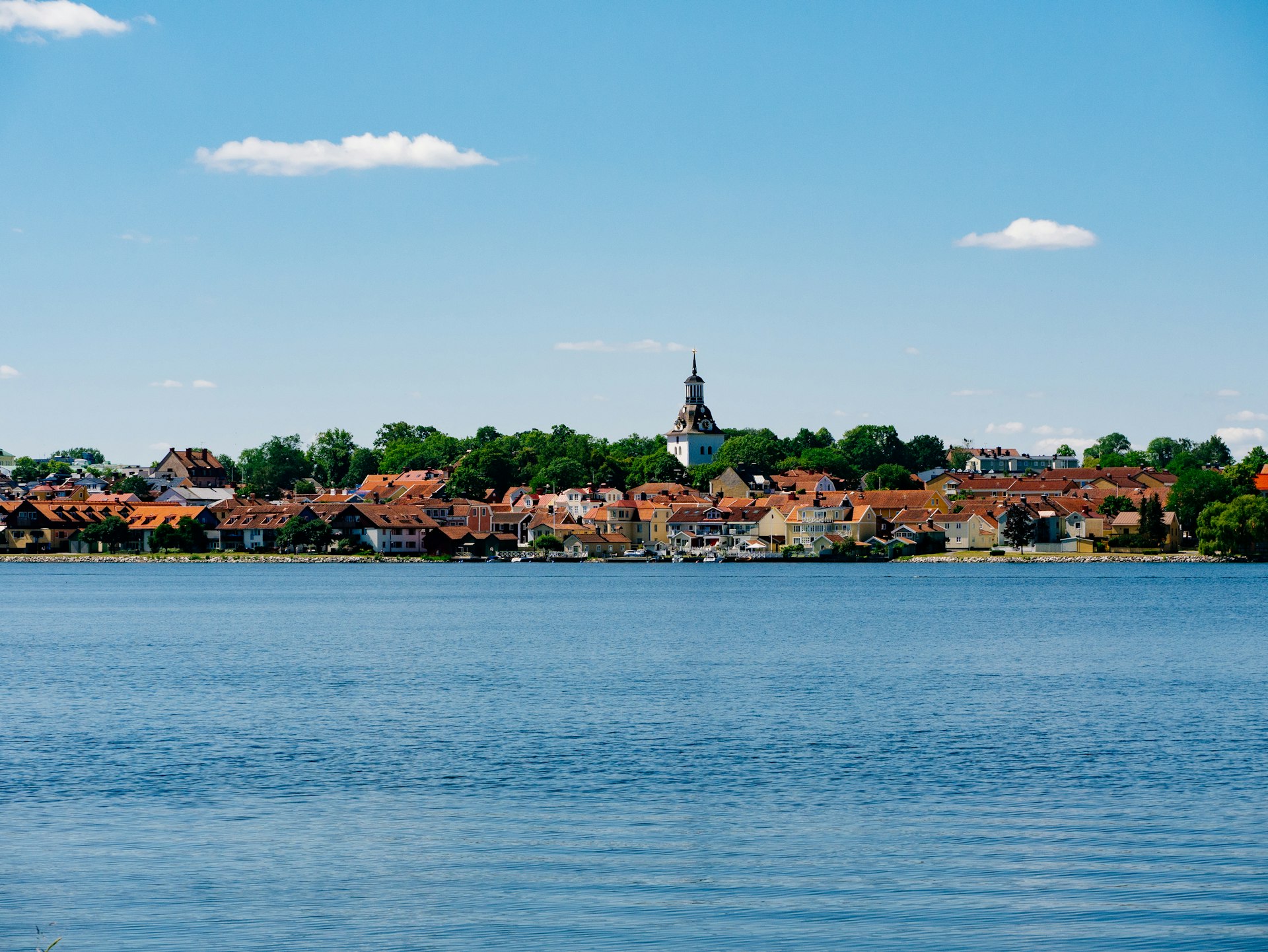 body of water near green trees and houses under blue sky during daytime