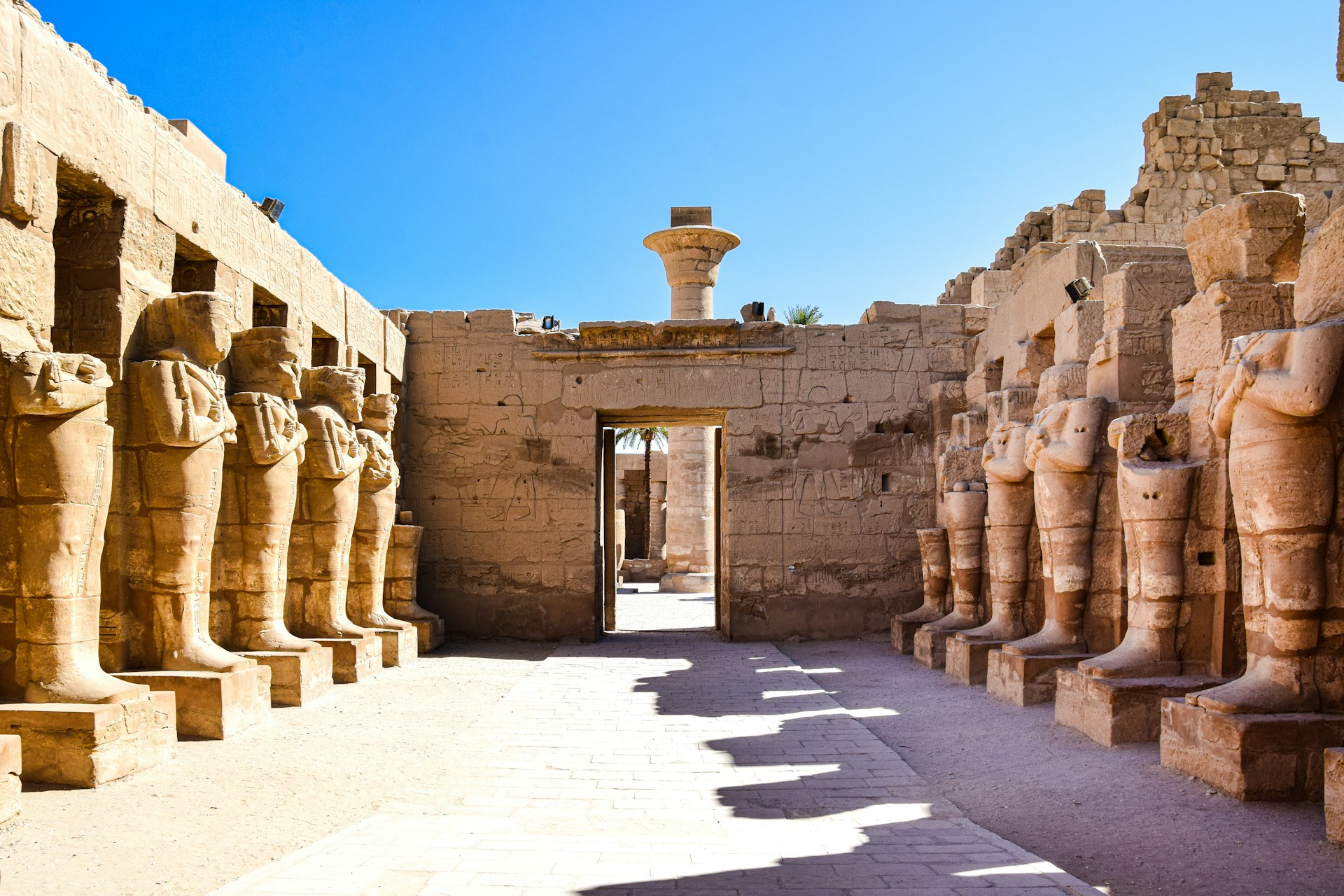 a stone building with pillars with Karnak in the background