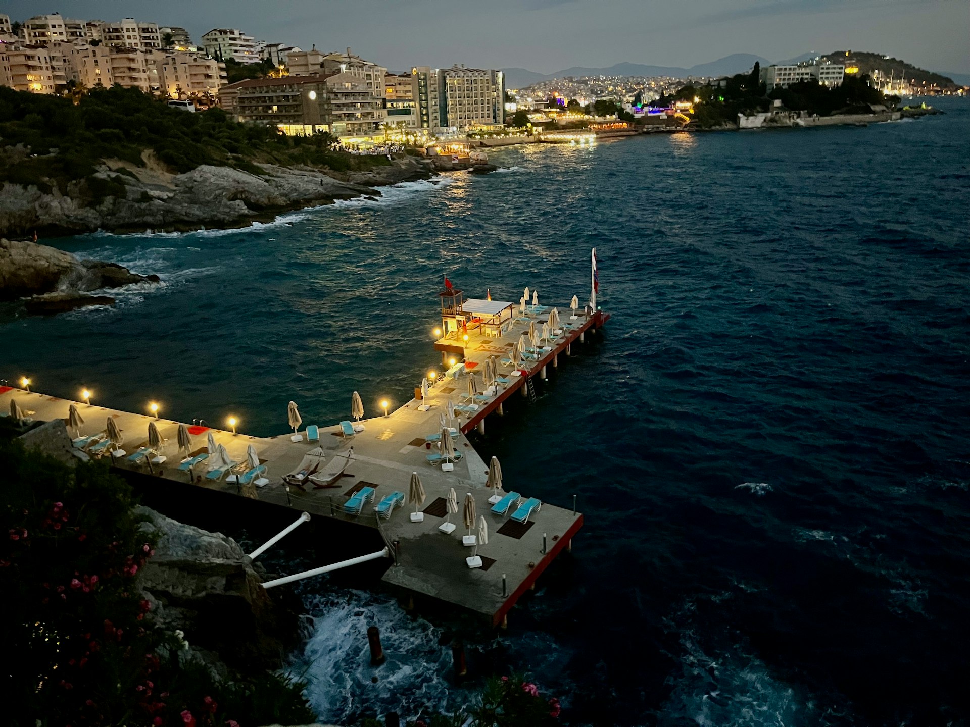 a dock with chairs and umbrellas on it next to the ocean