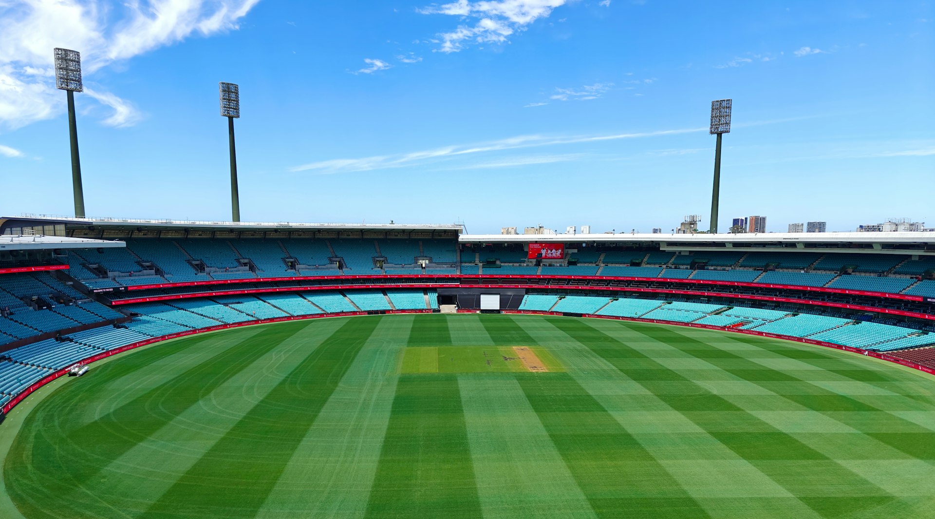 A cricket stadium with empty stands and a clear sky.