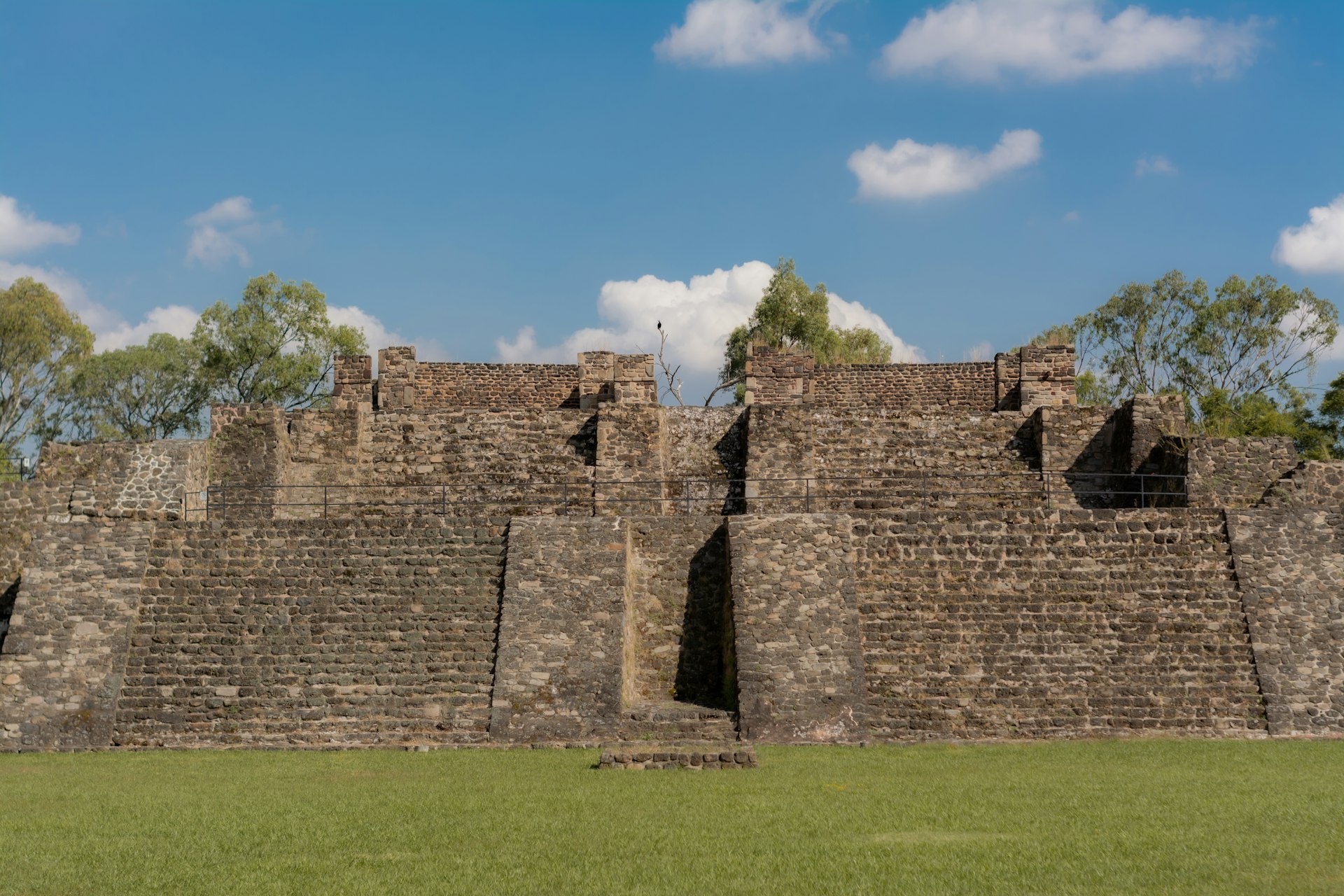 a stone wall with a grassy field in front of it